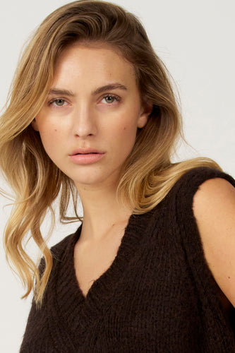 Portret jonge vrouw, bruin wollen vest, blond haar.
