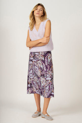 Vrouw in lila vest en paarse rok, gekruiste armen, zilveren schoenen.