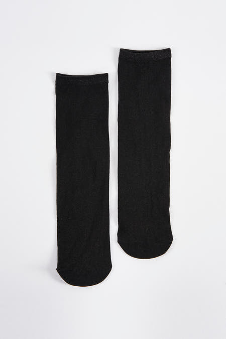 Chaussettes noires d'Astrid Black Label, avec des paillettes sur le bord, posées sur un fond blanc.