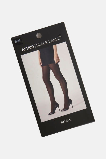 Panty brun de d'Astrid Black Label, présenté sur l'emballage avec une photo de jambes en escarpins noirs et jupe.