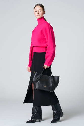 Blouse rose à col montant d'Astrid Black Label, portée avec une jupe noire à boutons et des bottes noires.
