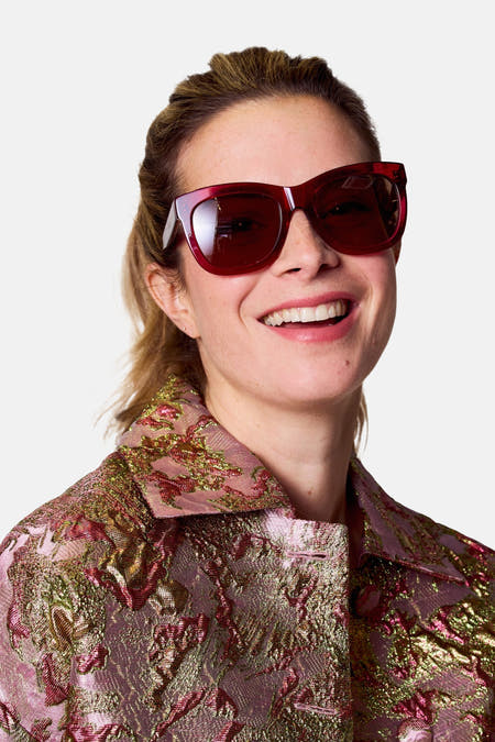 Lunettes de soleil roses d'Astrid Black Label, avec des verres marrons et un cadre anguleux.