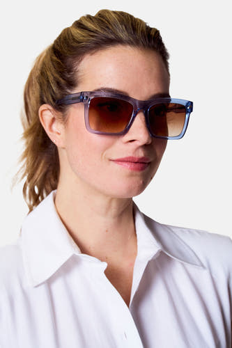 Lunettes de soleil bleues d'Astrid Black Label, portées par une femme en chemise blanche.