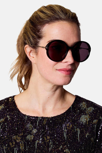 Lunettes de soleil noires d'Astrid Black Label, avec une forme ronde et des détails dorés.