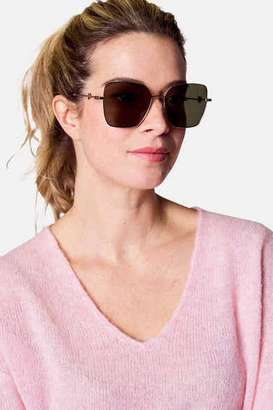 Lunettes de soleil roses d'Astrid Black Label, avec un cadre métallique et des verres dégradés, portées avec une chemise rose.
