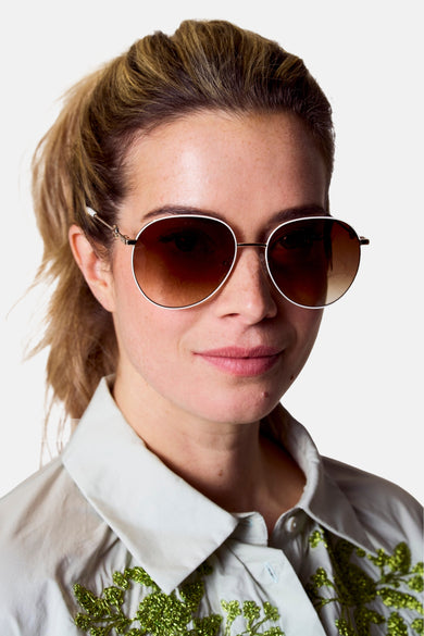 Lunettes de soleil blanches d'Astrid Black Label avec des verres bruns et des détails dorés.