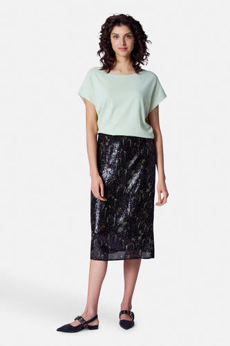 Robe noire d'Astrid Black Label, avec un motif pailleté, associée à une chemise verte claire et des chaussures noires.