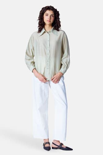 Blouse verte avec manches longues d'Astrid Black Label, portée avec un short blanc et des chaussures noires.