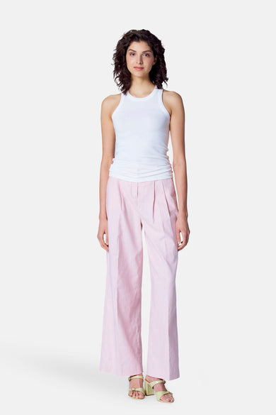 Vrouw draagt witte tanktop en gestreepte roze broek.