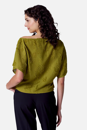 Vrouw in groene blouse en zwarte broek, achterkant.