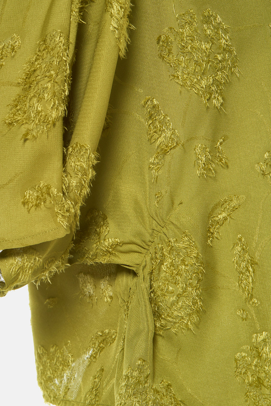 Olijfgroene blouse met decoratieve rafels.
