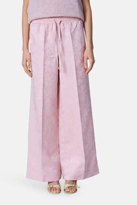 Pantalon rose Astrid Black Label avec une texture subtile et des jambes larges, porté avec des sandales.