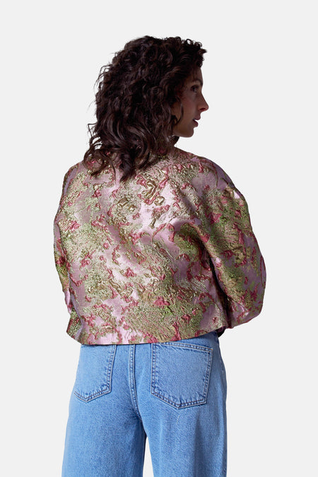 Manteau multicolore d'Astrid Black Label, avec un motif floral et porté avec des jeans bleus, vu de derrière.