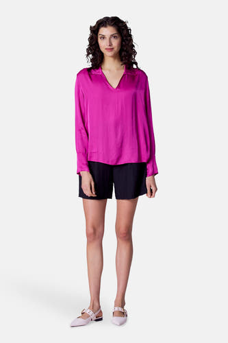 Blouse rose à longues manches d'Astrid Black Label, avec un col V et portée avec des short noirs et des chaussures roses.
