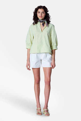 Blouse verte avec manches trois-quarts d'Astrid Black Label, avec un foulard et des shortts blancs.