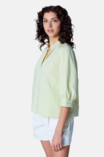 Groene blouse met driekwart mouwen van Astrid Black Label, met een open halslijn en witte shorts.

