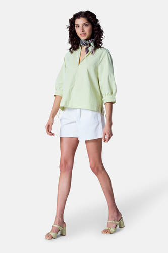 Blouse verte avec manches trois-quarts d'Astrid Black Label, associée à des short blancs et des sandales coordonnées.