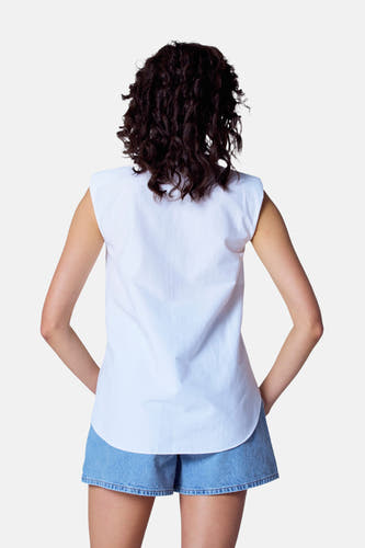 Blouse blanche à manches courtes d'Astrid Black Label, vue de l'arrière, associée à un short en denim.