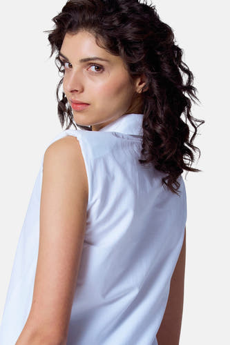Blouse blanche à manches courtes d'Astrid Black Label, avec une texture lisse et sans autres accessoires.