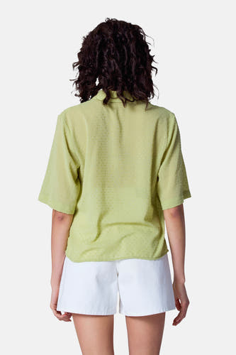 Groene blouse met korte mouwen van Astrid Black Label, met structuur en gedragen met een witte short.
