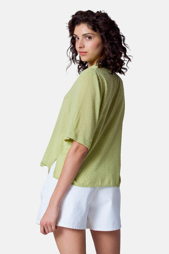 Blouse verte avec manches courtes d'Astrid Black Label, dotée d'une subtile texture à carreaux, portée avec des short blancs.