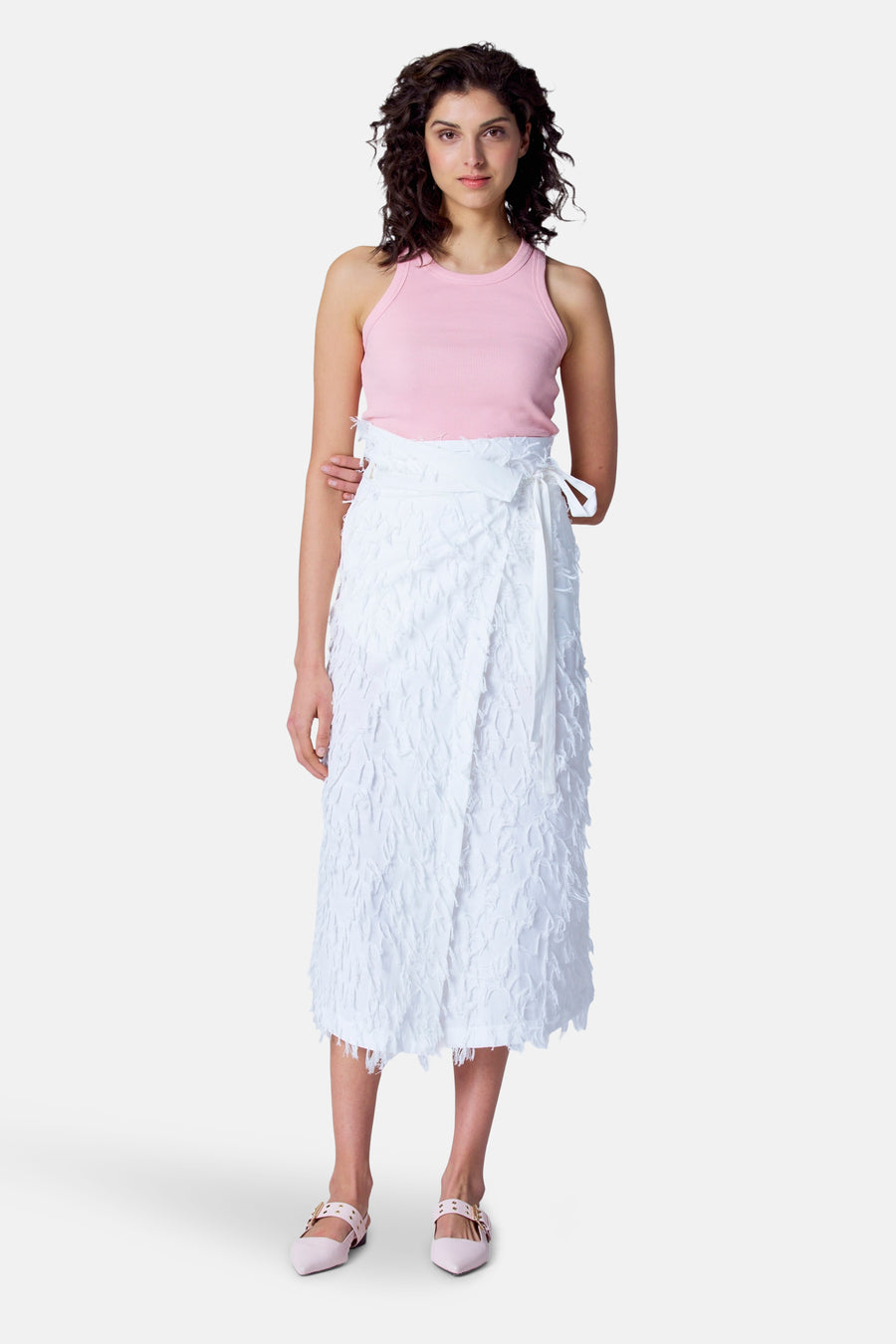 Vrouw met roze top en witte wikkelrok op witte achtergrond.