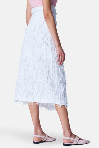 Robe blanche d'Astrid Black Label, avec des franges décoratives et une ligne de coupe asymétrique, vue de côté.