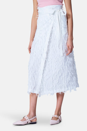 Dame in roze top en witte jurk met strikceintuur, roze schoenen.