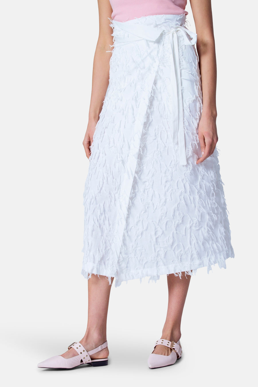 Dame in roze top en witte jurk met strikceintuur, roze schoenen.