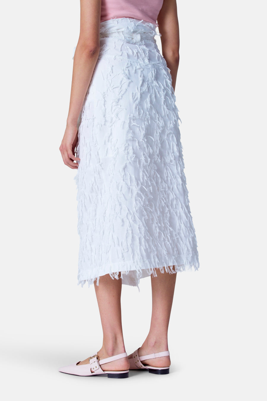 Vrouw in witte rok en roze schoenen.
