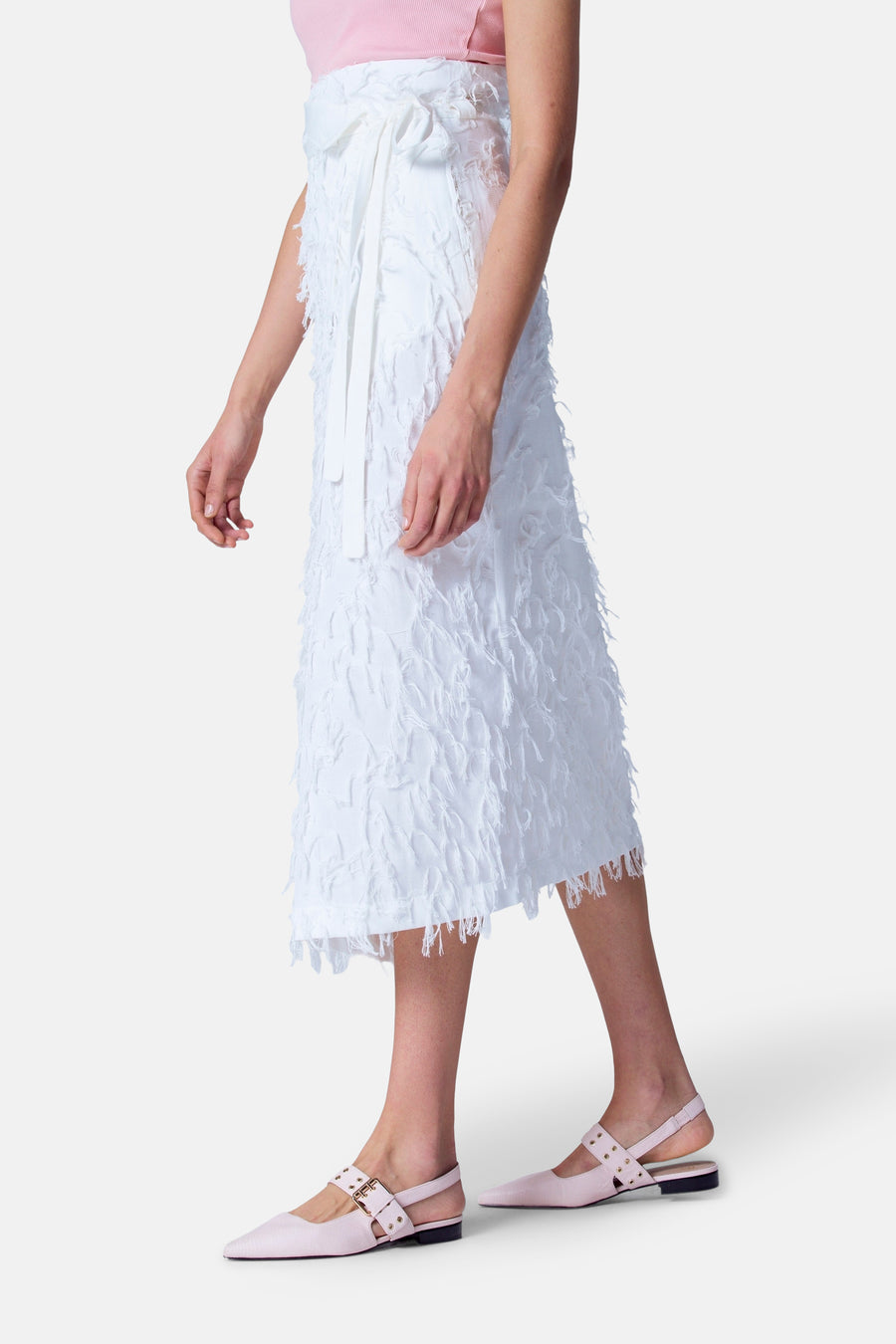 Vrouw in roze top en witte rok met franjes, roze Mary Jane-schoenen.