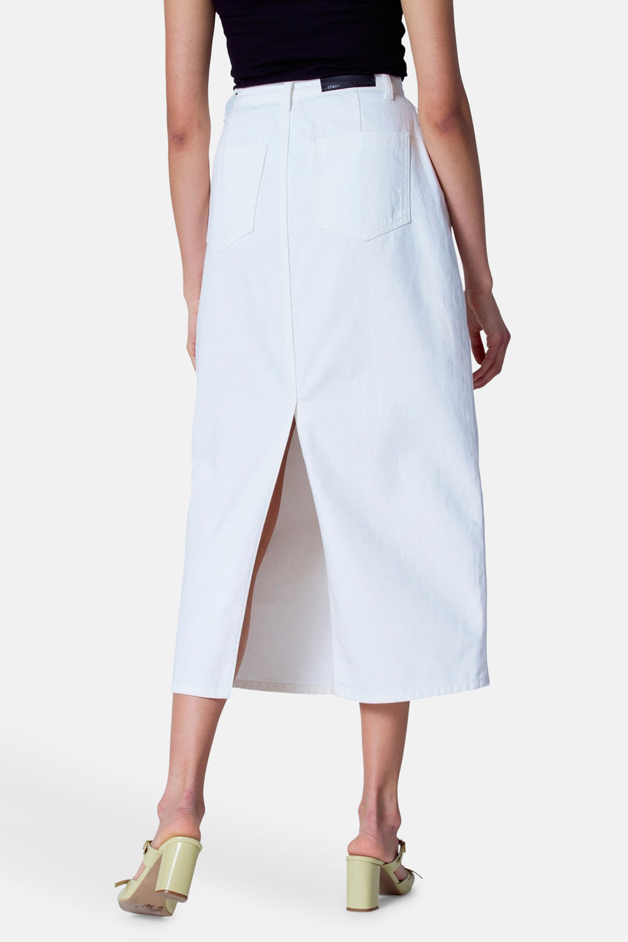 Witte denim rok met split en groene hakken.
