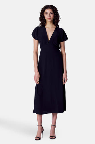 Robe noire à manches courtes d'Astrid Black Label, vue de derrière, avec une taille élastique et des talons noirs.