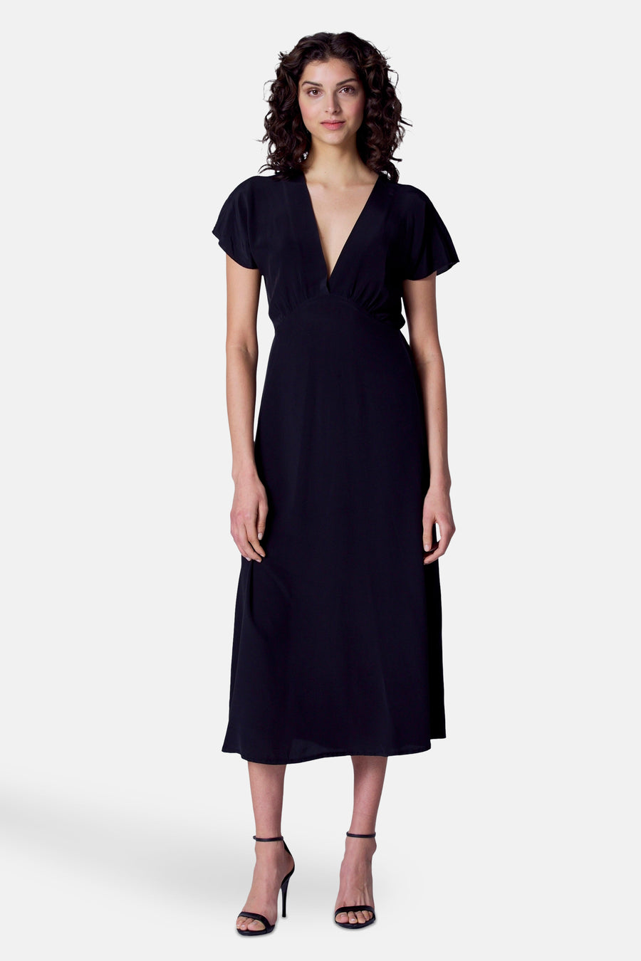 Robe noire à manches courtes d'Astrid Black Label, vue de derrière, avec une taille élastique et des talons noirs.