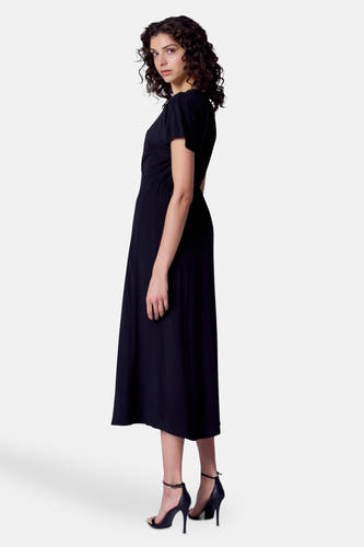 Robe noire à manches courtes d'Astrid Black Label, avec une taille plissée et des talons noirs.