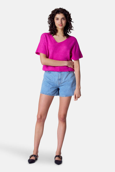 Short de denim bleu marine d'Astrid Black Label, porté avec un pull rose et des chaussures noires à boucles.
