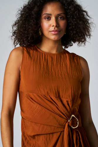 Jupe sans manches marron d'Astrid Black Label avec une devanture drapée et un détail de bague dorée.