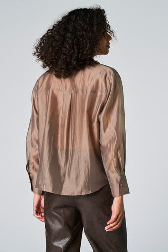 Blouse taupe à longues manches d'Astrid Black Label, avec plis et fermeture à boutons, associée à une jupe en cuir marron.