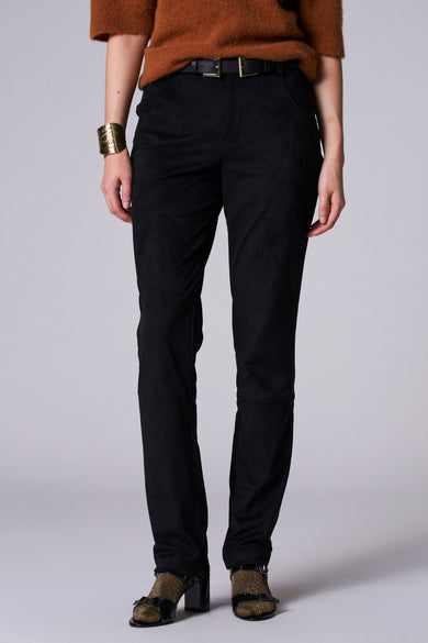 Zwarte broek van Astrid Black Label, met een gladde textuur, gecombineerd met een bruine trui, gouden armband en open schoenen.
