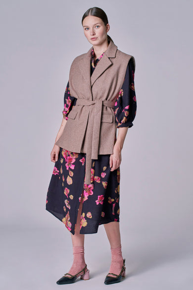 Blazer taupe d'Astrid Black Label, porté avec une robe à fleurs, des chaussettes roses et des chaussures noires.