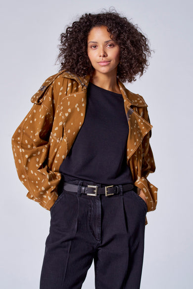 Manteau court brun d'Astrid Black Label, à carreaux, porté sur une chemise noire et un pantalon foncé avec une ceinture double.