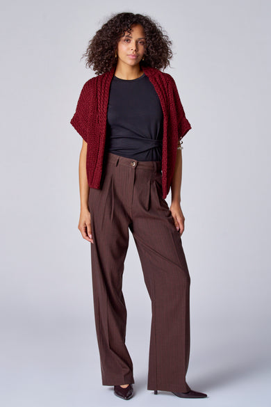 T-shirt noir à manches courtes d'Astrid Black Label, porté avec un pantalon marron et une veste bordeaux à manches courtes.