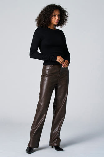 T-shirt noir à manches longues d'Astrid Black Label, porté avec un pantalon en cuir marron et des baskets noires.