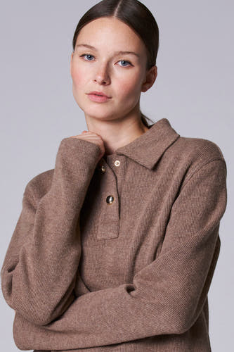 Veste taupe avec col V d'Astrid Black Label, avec des boutons dorés et des manches longues.