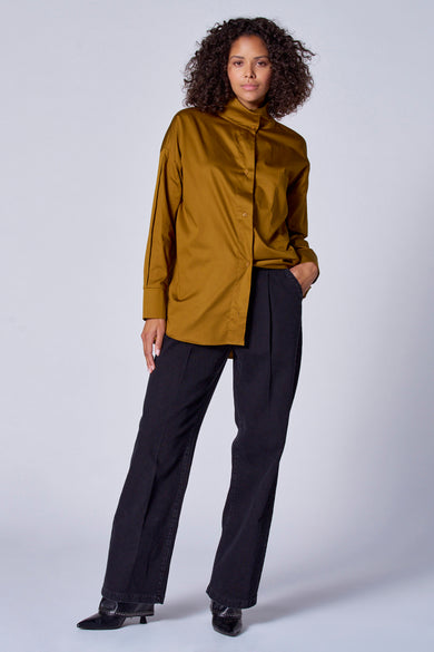 Blouse verte avec manches longues d'Astrid Black Label, portée avec un pantalon noir et des escarpins à strass.