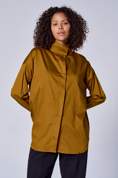 Blouse verte avec manches longues d'Astrid Black Label, à boutons et avec une poche poitrine, portéeéeée un pantalon.