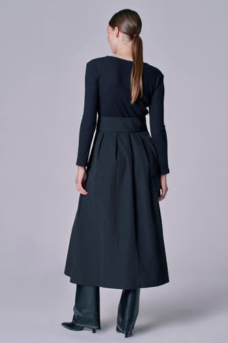 Robe noire à longues manches d'Astrid Black Label, associée à une jupe noire et des bottes en cuir.