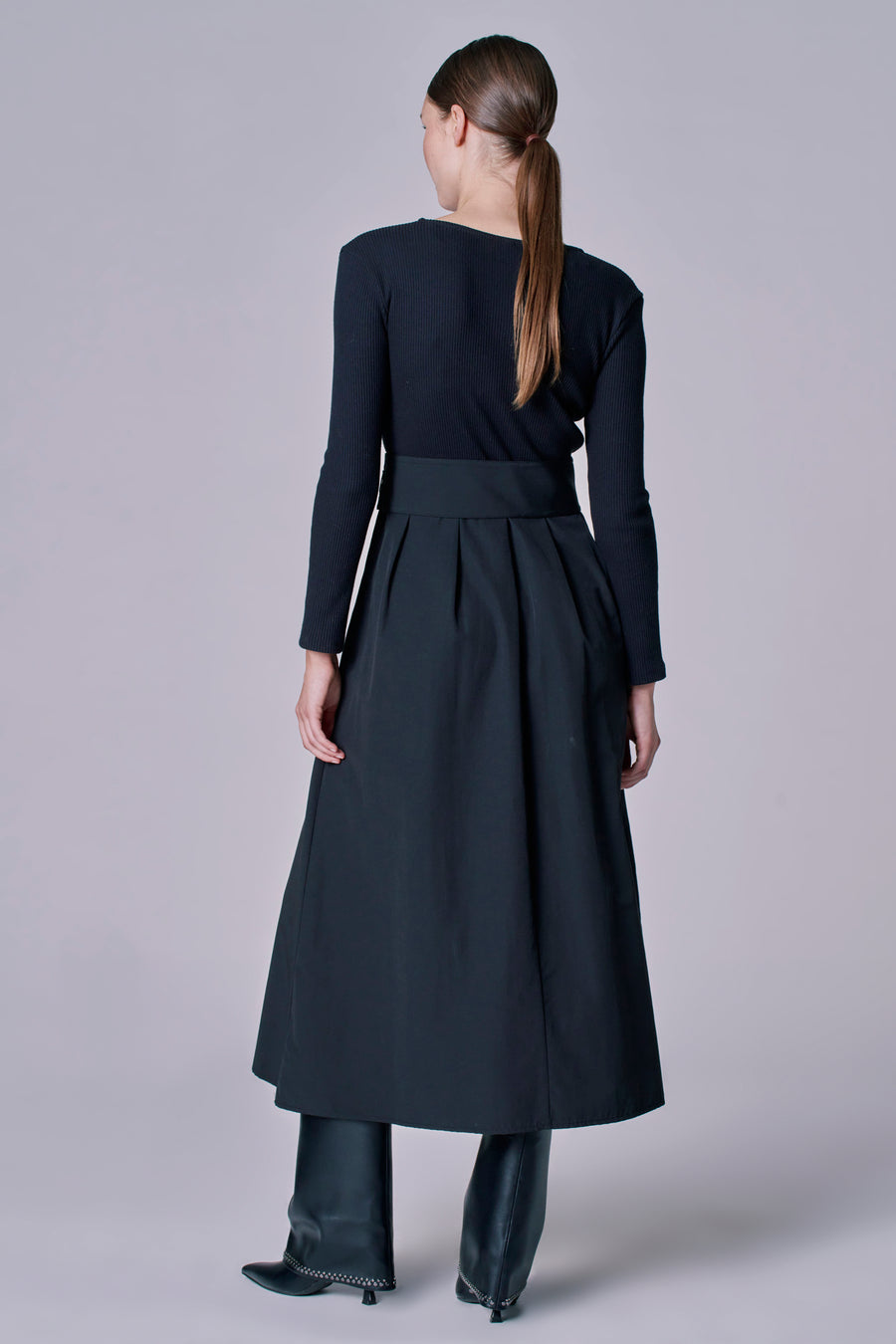 Robe noire à longues manches d'Astrid Black Label, associée à une jupe noire et des bottes en cuir.
