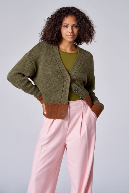 T-shirt vert avec col V d'Astrid Black Label, avec un bloc de couleur marron en bas et un pantalon rose.