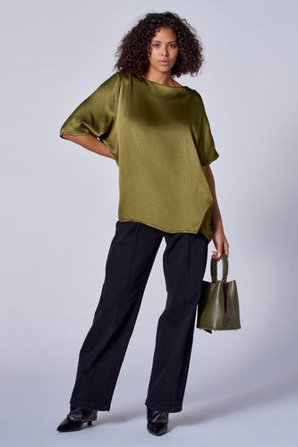 Blouse verte avec manches courtes d'Astrid Black Label, associée à une jupe noire et une poche verte.